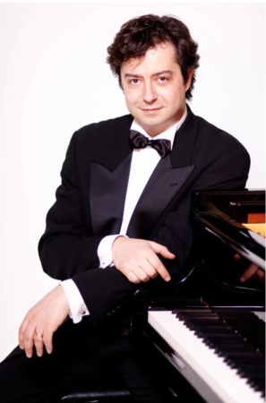 image of Fabio Bidini learning against a piano in a black tuxedo, white shirt and black bow tie